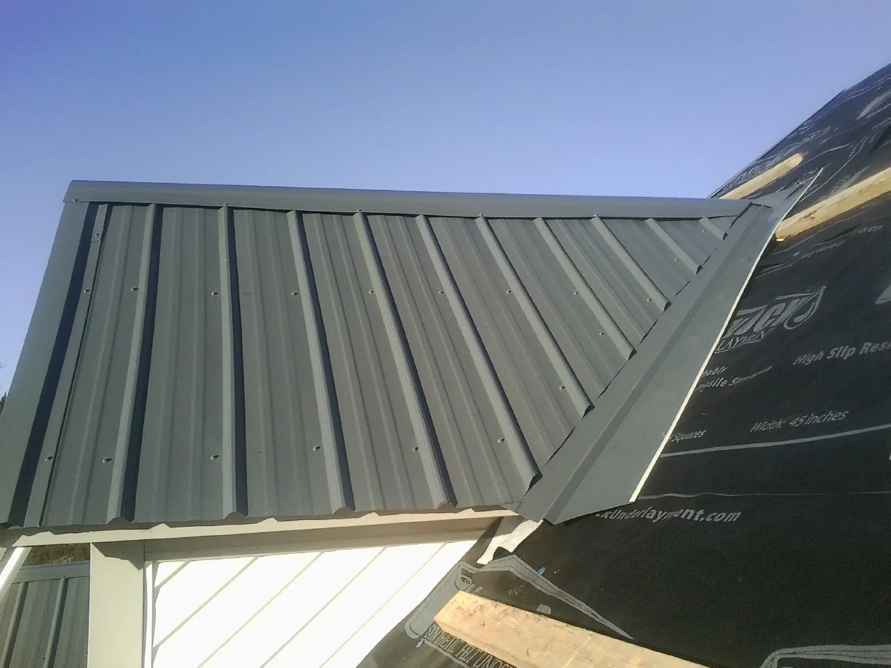 Gray metal roof panels going on over a garage gable in Thompson Falls