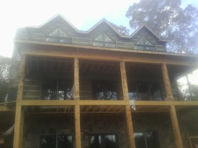 Dormers and porch framing on a large log home under construction — Roof Coating work by our crew in Thompson Falls
