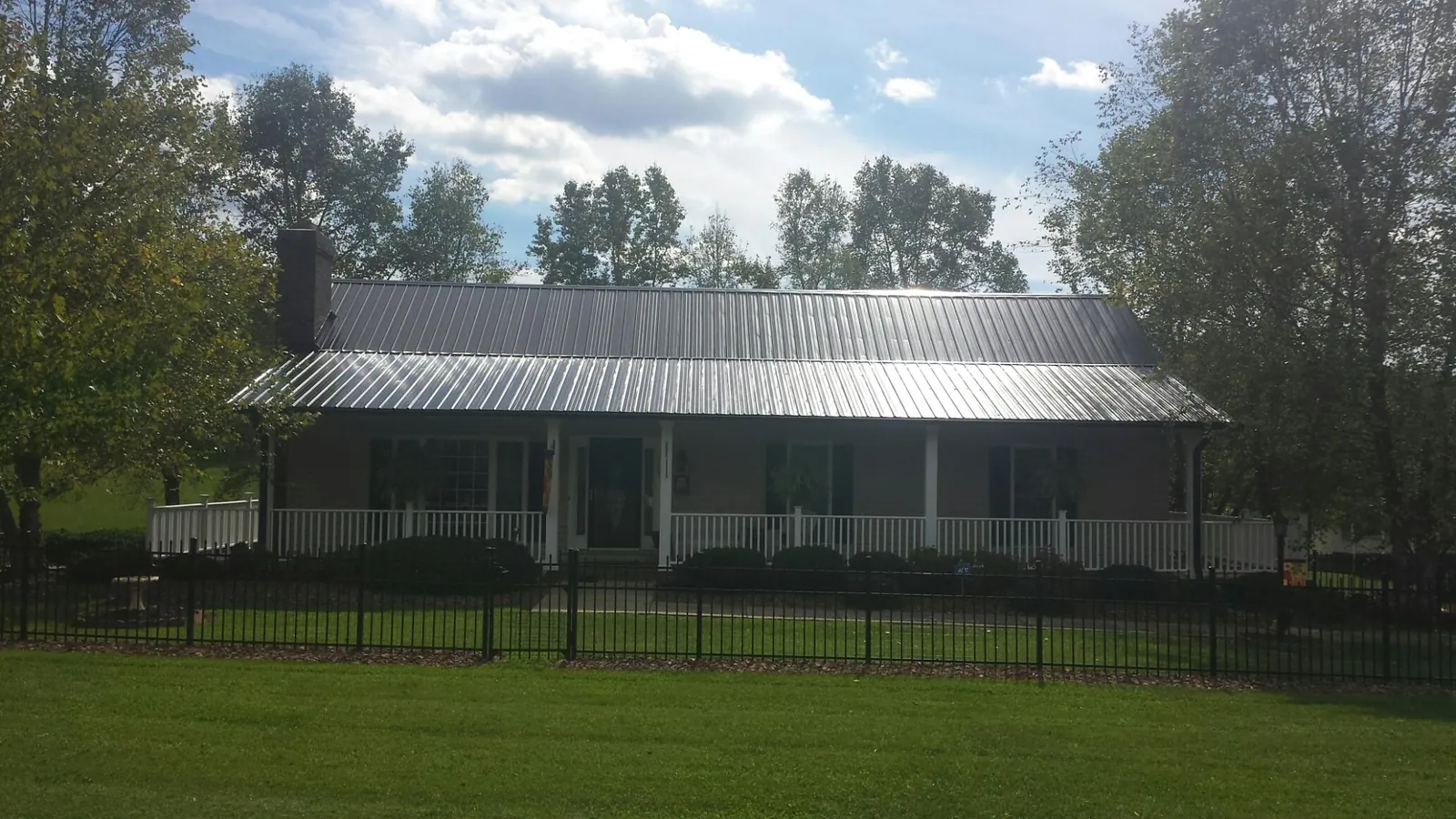 Gray metal roof on a brick ranch with a full width front porch — Gutter Guard Installation work by our crew in Thompson Falls