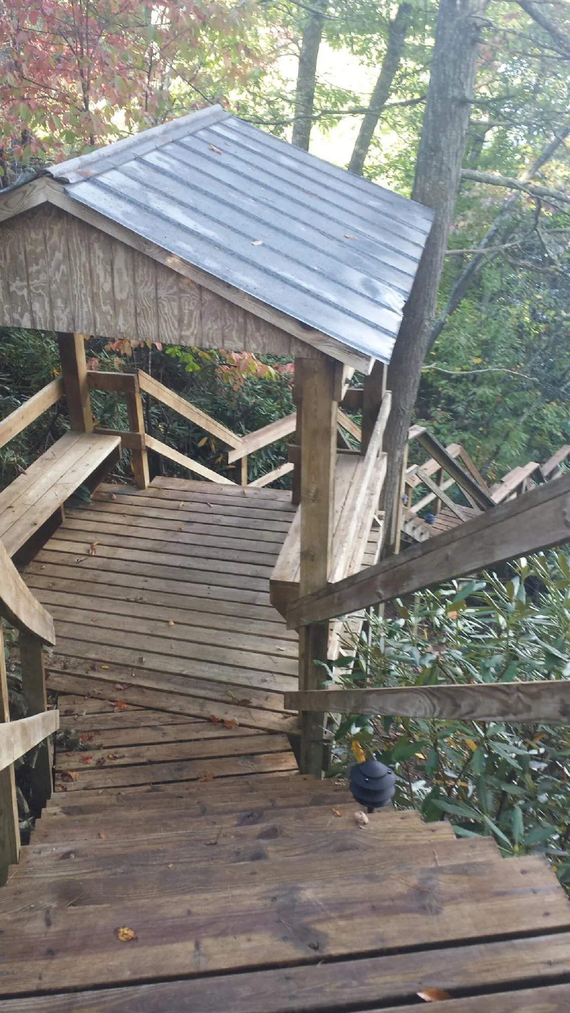 Metal roofed shelter over wooden steps on a wooded walkway — Skylight Repair & Installation work by our crew in Thompson Falls