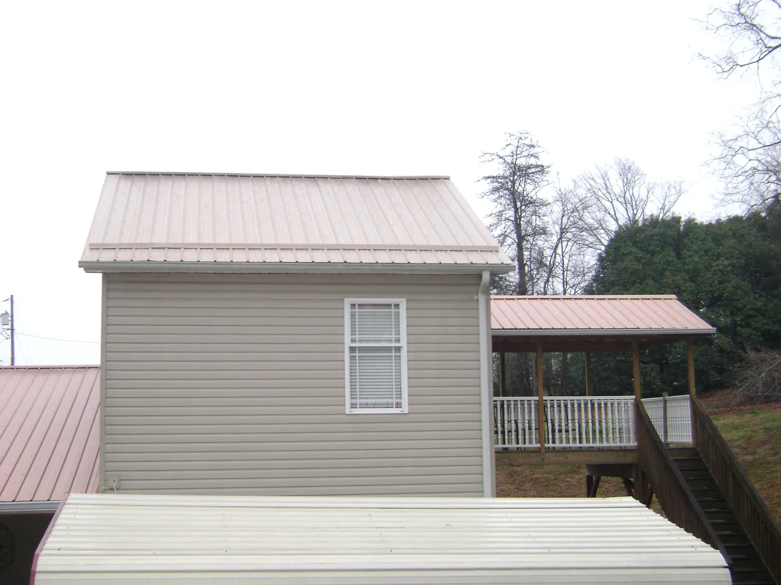 Tan metal roofs on a two story addition and attached porch, from a Roof Replacement job in Thompson Falls