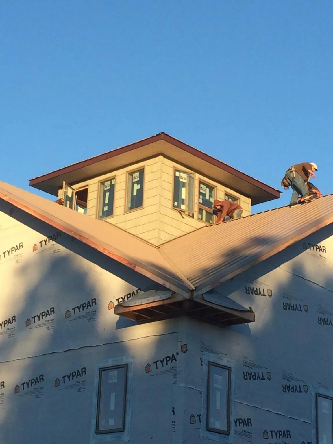 Roofers working around a rooftop cupola on a new metal roof at sunset — Roof Waterproofing in Thompson Falls by Roofing Brothers